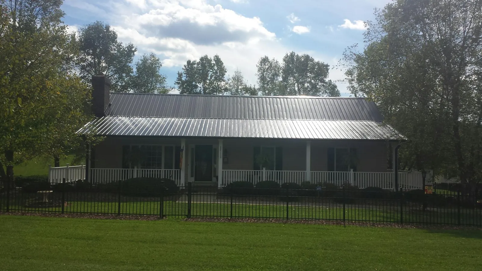 Gray metal roof on a brick ranch with a full width front porch — Gutter Guard Installation work by our crew in Bainbridge
