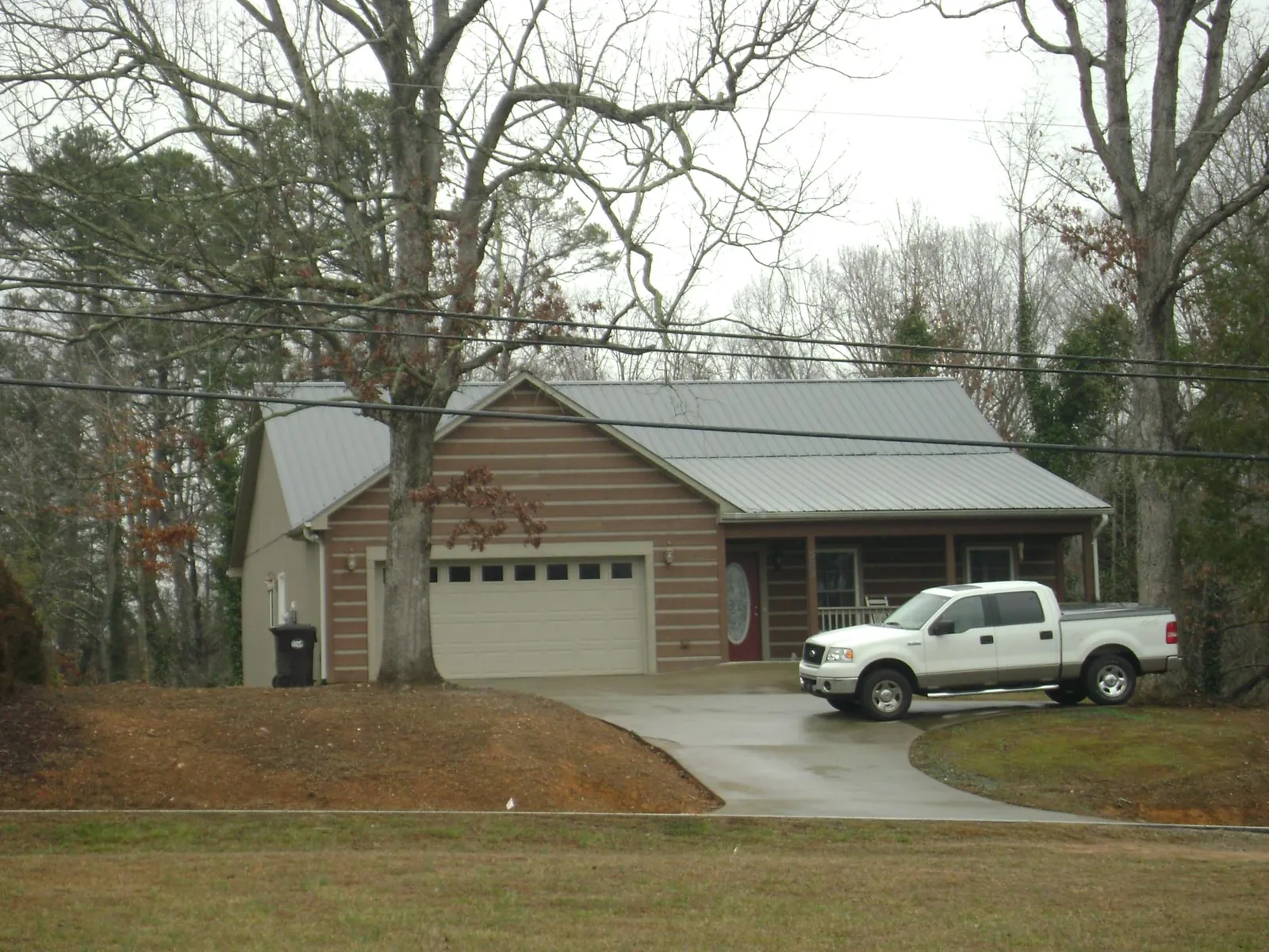 Gray metal roof on a log sided house with an attached two car garage in Bainbridge